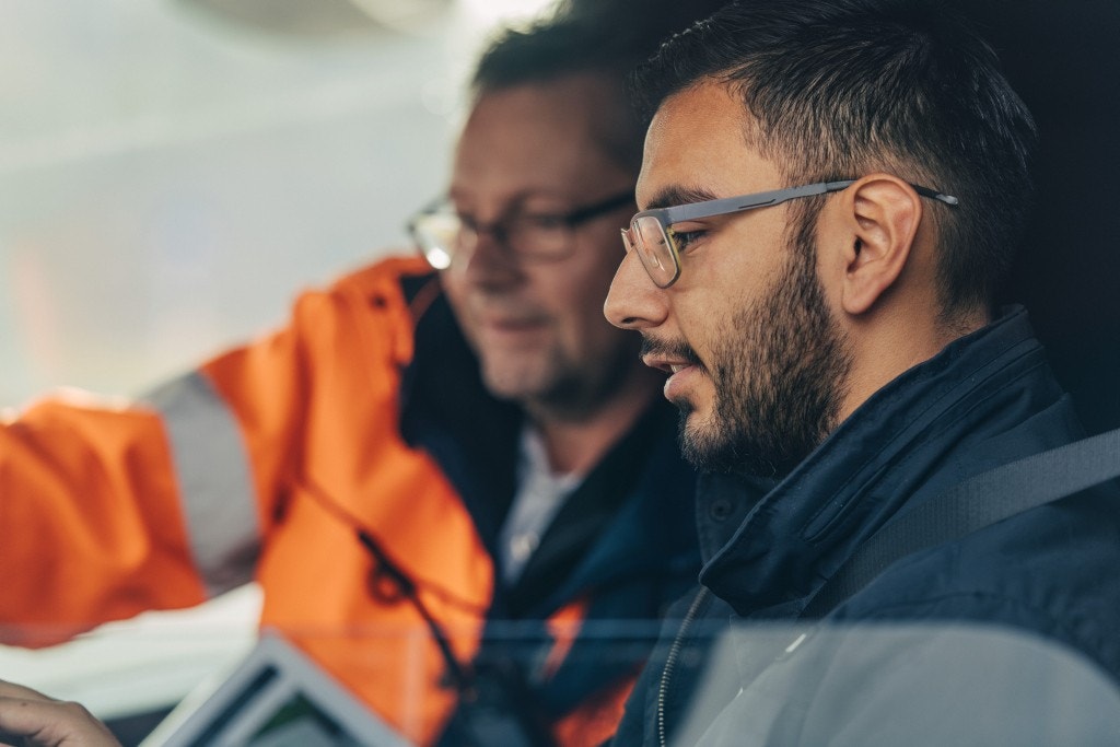  Drei Personen vor Monitoren