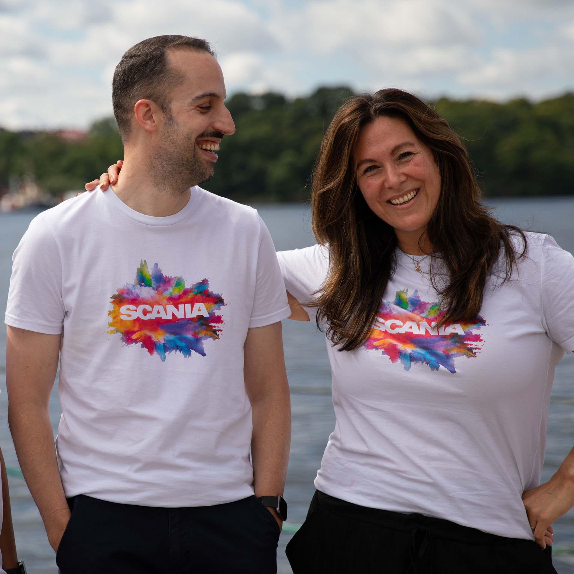 Two smiling Scania employees at Stockholm Pride in front of the water