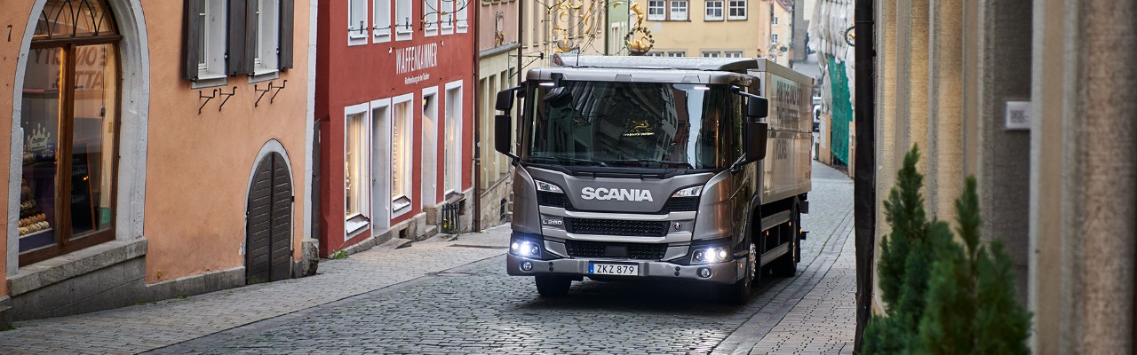 Model Scania L-serije u vožnji kroz malu ulicu